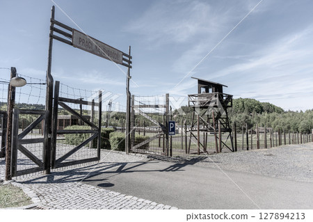 The entrance gate of the former Vojna prison complex in Lesetice, Czechia stands as a stark reminder of its historical past. The surrounding area is tranquil, with trees and a gravel path. 127894213