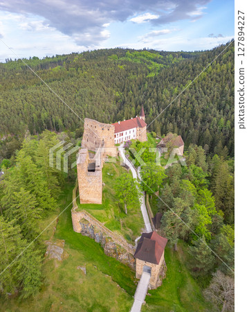 Drone captures Velhartice Castle surrounded by dense forests in the Czech Republic. This historical site features impressive stone structures and a winding pathway, showcasing scenic beauty. 127894227