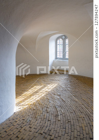 Visitors ascend the spiral ramp of the Round Tower, experiencing a unique architectural feature. The warm sunlight filters through the tall windows, illuminating the brick pathway. Visitors ascend the spiral ramp of the Round Tower, experiencing a unique architectural feature. The warm sunlight filters through the tall windows, illuminating the brick pathway. 127894247