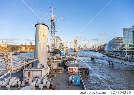 View from the deck of HMS Belfast showcasing the iconic Tower Bridge and the modern London skyline. The river flows beneath with boats navigating the busy waterway. View from the deck of HMS Belfast showcasing the iconic Tower Bridge and the modern London skyline. The river flows beneath with boats navigating the busy waterway. 127894259