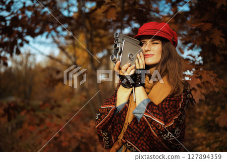 elegant woman in red hat with retro video camera and scarf elegant woman in red hat with retro video camera and scarf 127894359