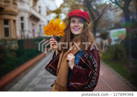 happy elegant female in red hat with autumn leafs and scarf 127894366