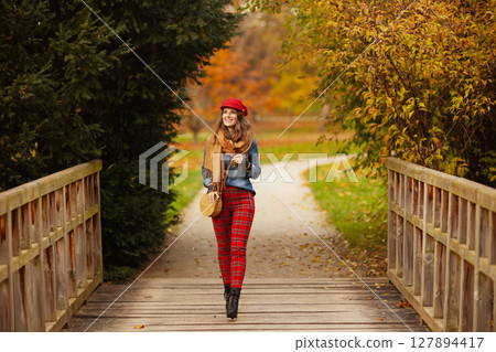 smiling modern woman in jeans shirt and red hat walking smiling modern woman in jeans shirt and red hat walking 127894417