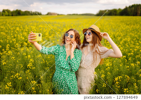 Selfie time.Two Young woman takes selfie while walking flowering field. Nature, relax and lifestyle. Selfie time.Two Young woman takes selfie while walking flowering field. Nature, relax and lifestyle. 127894649