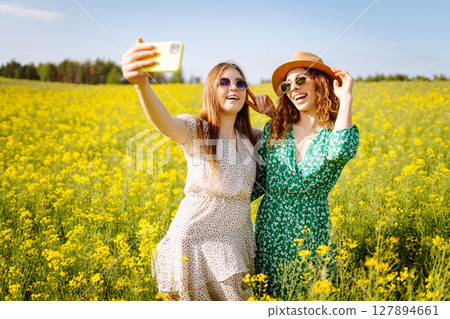 Selfie time.Two Young woman takes selfie while walking flowering field. Nature, relax and lifestyle. Selfie time.Two Young woman takes selfie while walking flowering field. Nature, relax and lifestyle. 127894661