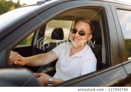 Young couple in new car is relaxing in sunset. Man has fun with girl in car at wheel Travel, tourism Young couple in new car is relaxing in sunset. Man has fun with girl in car at wheel Travel, tourism 127894790
