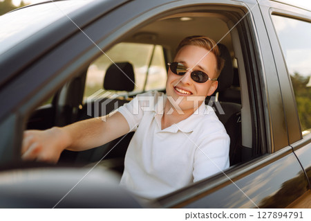 Young couple in new car is relaxing in sunset. Man has fun with girl in car at wheel Travel, tourism Young couple in new car is relaxing in sunset. Man has fun with girl in car at wheel Travel, tourism 127894791
