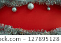 Christmas background with copy space in the center. Christmas balls and tinsel on a red background. 127895128