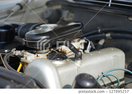 The engine and battery compartment of a classic car, with its detailed mechanical and electrical components, the vintage engineering powering the vehicle. The engine and battery compartment of a classic car, with its detailed mechanical and electrical components, the vintage engineering powering the vehicle. 127895257