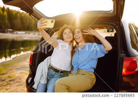 Portrait of two young women on a car trip having fun. Active lifestyle, travel, tourism, nature. 127895665