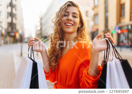 Young woman with shopping bags near mall. Purchases, shopping, lifestyle, sale concept. 127895897