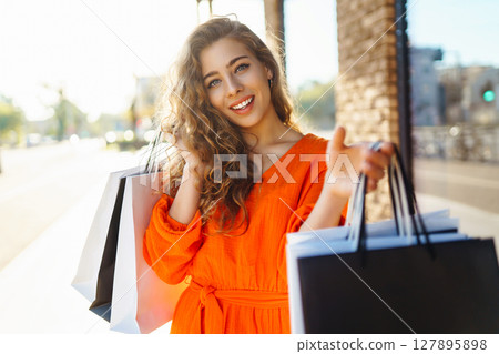 Young woman with shopping bags near mall. Purchases, shopping, lifestyle, sale concept. 127895898