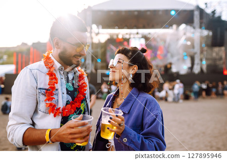 Young and cheerful couple at music festival. Happy friends drinking beer and having fun. Young and cheerful couple at music festival. Happy friends drinking beer and having fun. 127895946