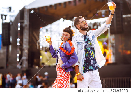 Young and cheerful couple at music festival. Happy friends drinking beer and having fun. Young and cheerful couple at music festival. Happy friends drinking beer and having fun. 127895953