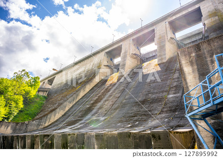 Orlik Dam and Hydroelectric Power Station in Czechia showcases its massive concrete structure under bright skies, harnessing river flow for energy generation in a scenic landscape. Orlik Dam and Hydroelectric Power Station in Czechia showcases its massive concrete structure under bright skies, harnessing river flow for energy generation in a scenic landscape. 127895992