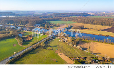 Bohumil Hrabal's Bridge elegantly stretches over the Labe River in Litol, Lysa nad Labem, surrounded by lush green fields and serene landscapes during a clear day. 127896015