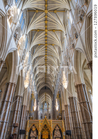 Westminster Abbey showcases intricate gothic design with soaring arches and detailed craftsmanship. Sunlight filters through stained glass, illuminating this historic place of worship in London. Westminster Abbey showcases intricate gothic design with soaring arches and detailed craftsmanship. Sunlight filters through stained glass, illuminating this historic place of worship in London. 127896019