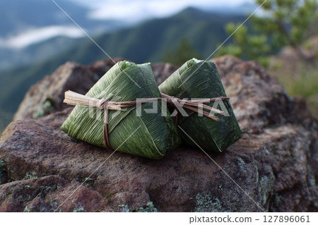 Handmade rice balls wrapped in bamboo leaves placed on a rocky mountain outcrop 127896061