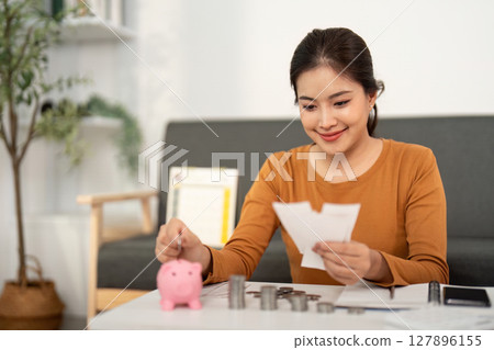 Budgeting: Woman Counting Money with Piggy Bank 127896155