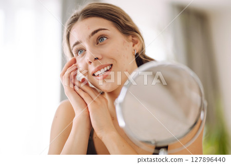 Woman worry about her face when she saw the problem of acne occur by a mini mirror. Pimples, acne 127896440