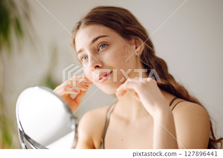 Woman worry about her face when she saw the problem of acne occur by a mini mirror. Pimples, acne Woman worry about her face when she saw the problem of acne occur by a mini mirror. Pimples, acne 127896441