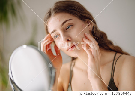 Woman worry about her face when she saw the problem of acne occur by a mini mirror. Pimples, acne 127896443