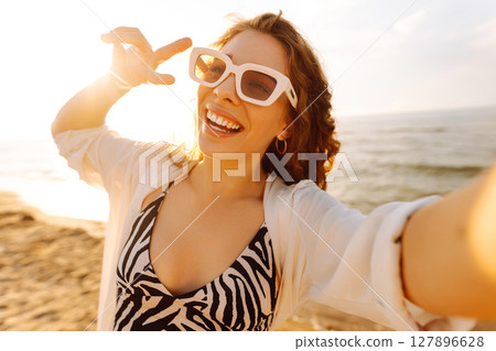 Portrait of young woman using smart phone selfie live on the beach. Travel and lifestyle concept. Portrait of young woman using smart phone selfie live on the beach. Travel and lifestyle concept. 127896628