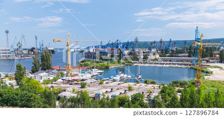 Vivid view of a seaport featuring cranes, docked boats, and lush greenery Vivid view of a seaport featuring cranes, docked boats, and lush greenery 127896784