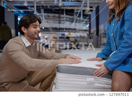 A couple engaging in the process of shopping for a new mattress at a furniture showroom 127897011
