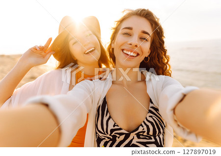 Two pretty friends women making selfie on beach, light and bright summer colors. Friends together Two pretty friends women making selfie on beach, light and bright summer colors. Friends together 127897019