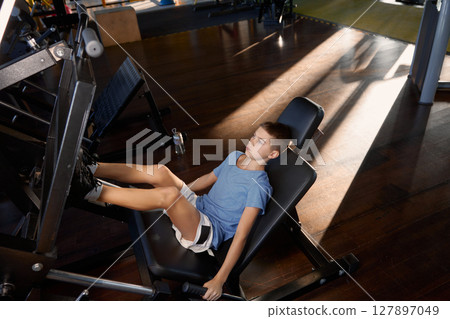 Teenage boy training legs at platform press strength machine Teenage boy training legs at platform press strength machine 127897049