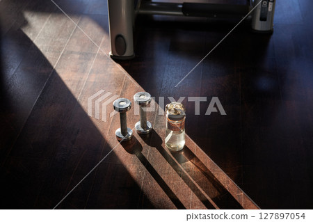 Pair of dumbbells and water sport bottle on floor of modern fitness club 127897054