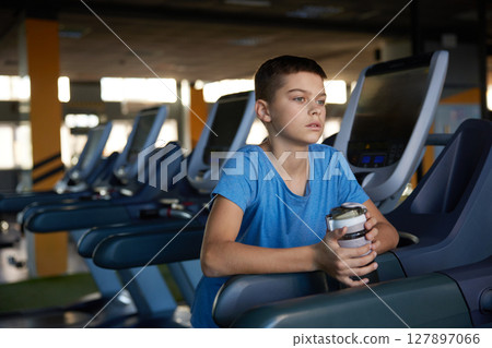 Pensive tired boy relaxing after cardio training on treadmill at sport club 127897066