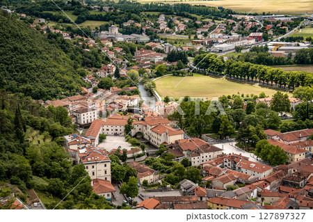 Picturesque View Of Vipava From Castle Ruins: Red-Tiled Rooftops And Church Tower Nestled In Green Valley With Blooming Flowers In Foreground And Rolling Fields In Background, Slovenia Picturesque View Of Vipava From Castle Ruins: Red-Tiled Rooftops And Church Tower Nestled In Green Valley With Blooming Flowers In Foreground And Rolling Fields In Background, Slovenia 127897327