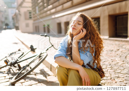 Portrait of smiling woman sitting next to bike on street city. Travel, weekend and lifestyle concept Portrait of smiling woman sitting next to bike on street city. Travel, weekend and lifestyle concept 127897711