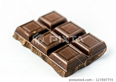 Closeup of a segmented dark chocolate bar with a subtle sheen, lying on a solid white background 127897755