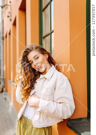 Optimistic woman with curly hair walking on the street city. Concept of lifestyle, fashion, travel. 127897857