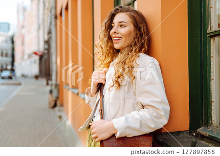 Optimistic woman with curly hair walking on the street city. Concept of lifestyle, fashion, travel. Optimistic woman with curly hair walking on the street city. Concept of lifestyle, fashion, travel. 127897858