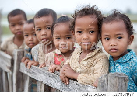 Group of asian children leaning on wooden fence in rural landscape 127897987