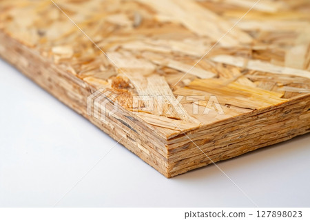 Single OSB oriented strand board panel is laying on a white surface, showing the layers of wood chips 127898023