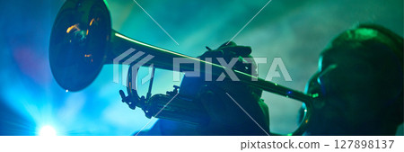 Musician playing trumpet on stage with dramatic green and blue lighting Musician playing trumpet on stage with dramatic green and blue lighting 127898137