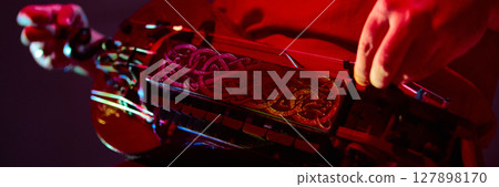 Close-up of hands playing ornate hurdy-gurdy under dramatic red lighting 127898170