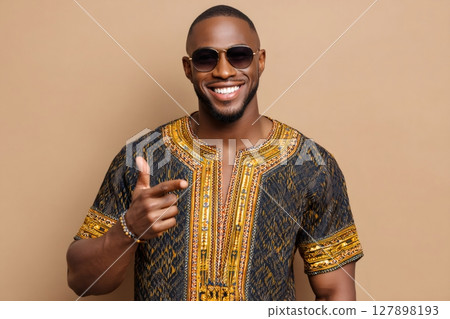 Smiling young man wearing dashiki and sunglasses pointing finger at you 127898193