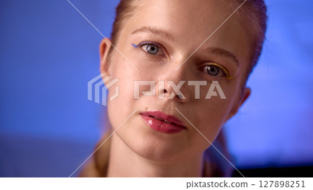 Young woman in relaxed pose with soft lighting and blue neon background ambiance Young woman in relaxed pose with soft lighting and blue neon background ambiance 127898251