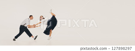 Vintage lindy hop dancers performing energetic swing dance move in retro attire. Banner 127898297
