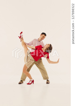Lindy hop dancers in vintage attire performing energetic retro swing dance moves 127898322