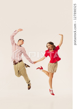 Retro couple energetically dancing lindy hop with joyful expressions and coordinated outfits Retro couple energetically dancing lindy hop with joyful expressions and coordinated outfits 127898325