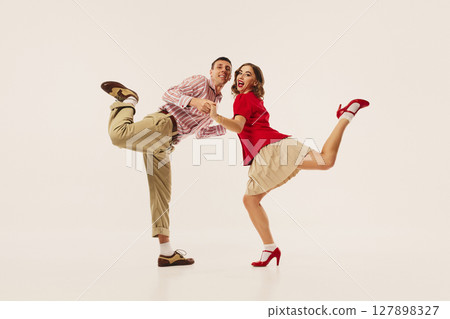 Retro couple joyfully performing energetic lindy hop dance moves on plain white background 127898327