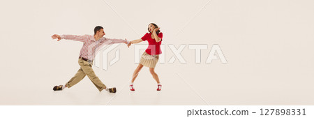 Couple joyfully performing retro lindy hop dance in vintage fashion against plain background. Banner Couple joyfully performing retro lindy hop dance in vintage fashion against plain background. Banner 127898331