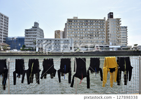 Wetsuits hung out to dry in front of a surfing class on Katase Enoshima Island Wetsuits hung out to dry in front of a surfing class on Katase Enoshima Island 127898338
